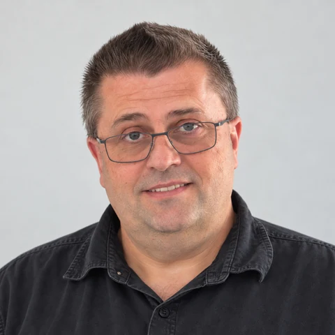 Head-and-shoulders portrait of Mietek Najda, Hiteck Lift Services lift technician, wearing glasses and a dark work shirt